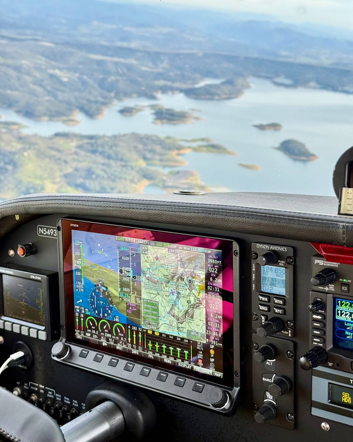 Glass-cockpit avionics panel in flight over a lake